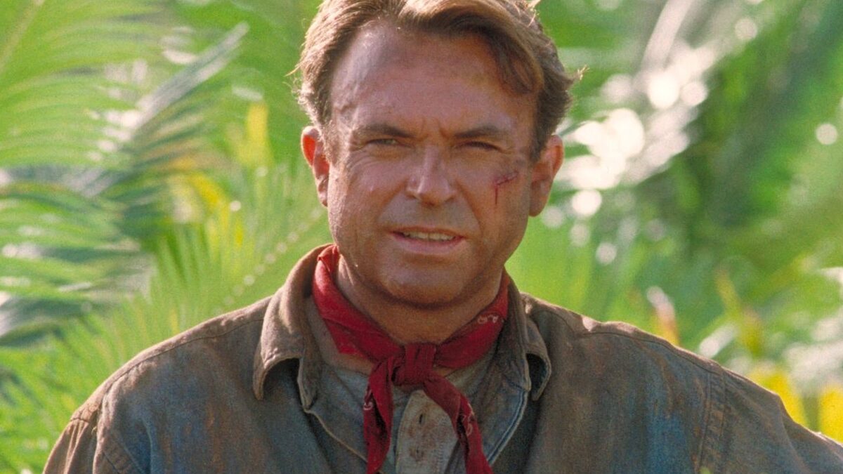 Sir Sam Neill smiling at a recent red carpet event, representing his legendary career as Dr. Alan Grant in Jurassic Park.